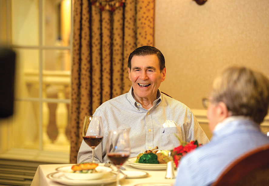 A man enjoying a meal with a glass of wine.