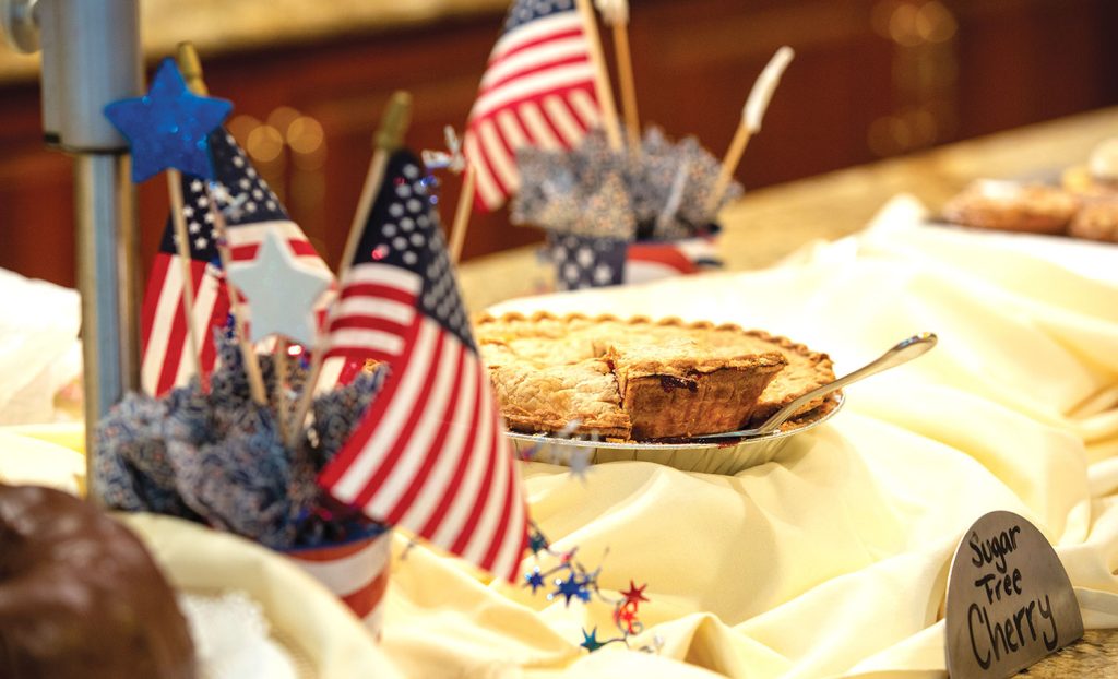 Cherry pie sitting on a dessert table with American flags.