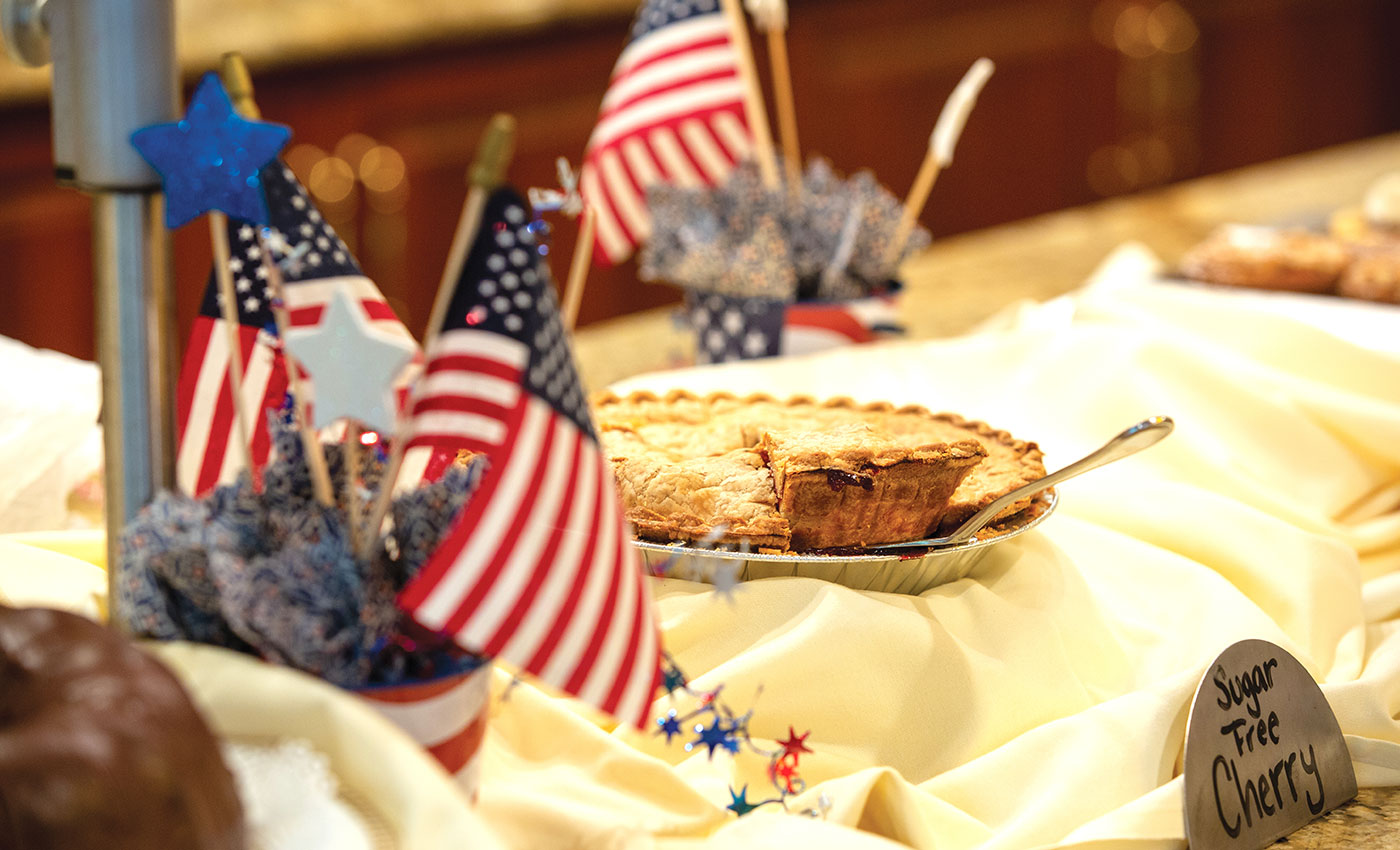 Cherry pie sitting on a dessert table with American flags.