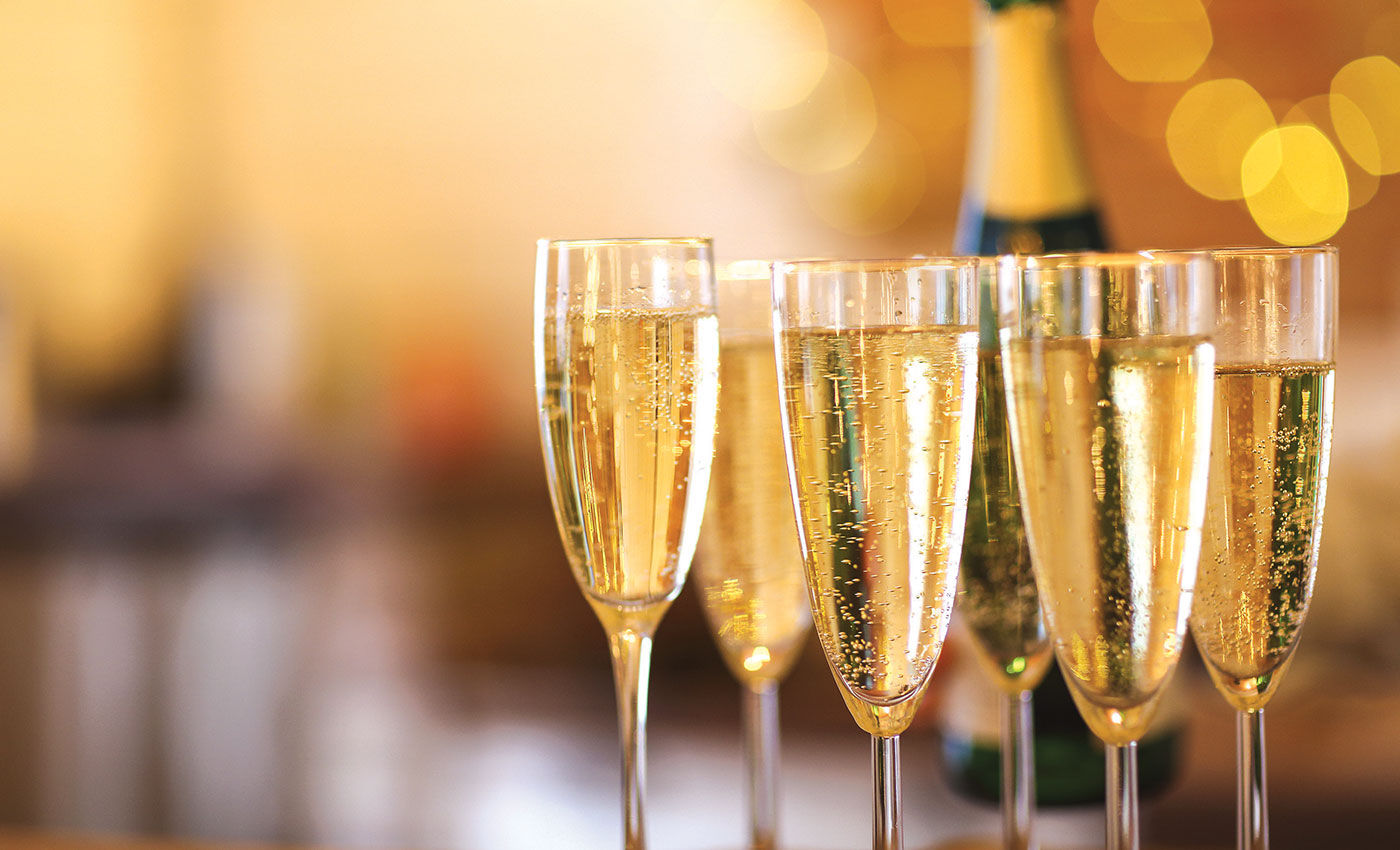 A close up of full champagne glasses with lights in the background.