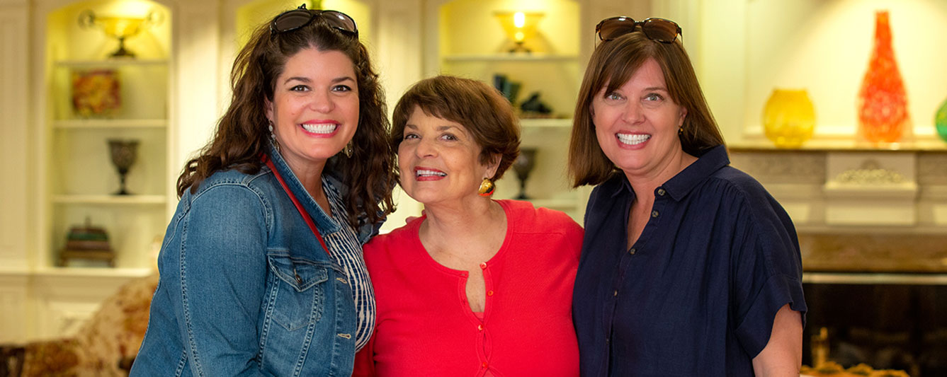 A mother smiling to the camera with her daughters.