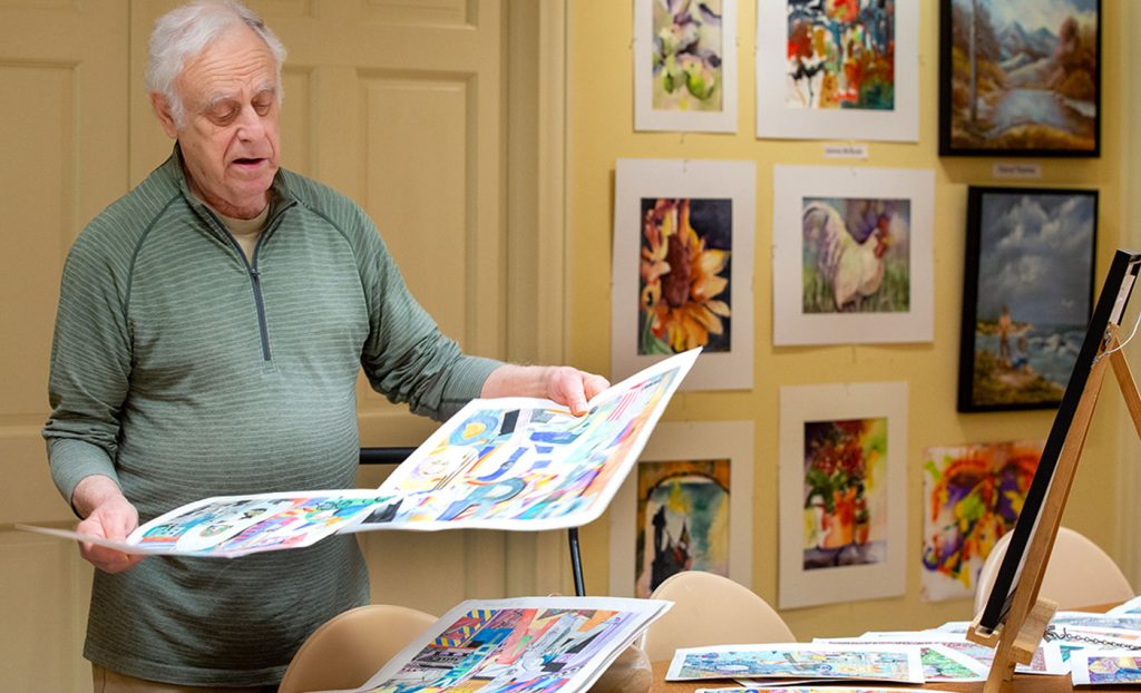 A man looks over his collection of artwork.