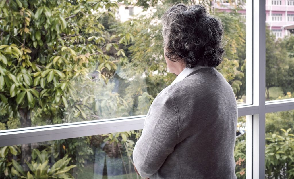 A woman looks out her window on an overcast day thinking.