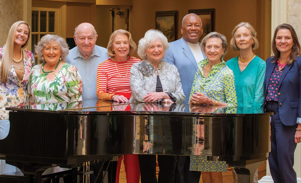 Resident ambassadors standing around a piano.