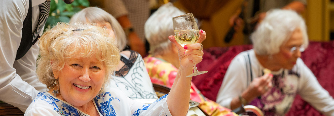 Woman raising a wine glass and smiling.