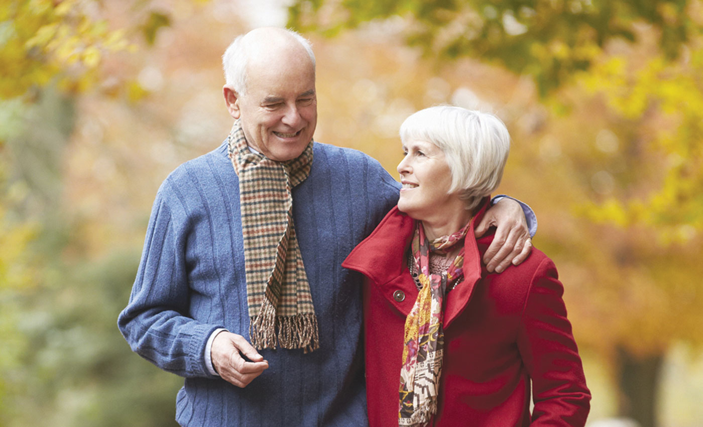 A couple walking outdoors in the fall weather with scarves.