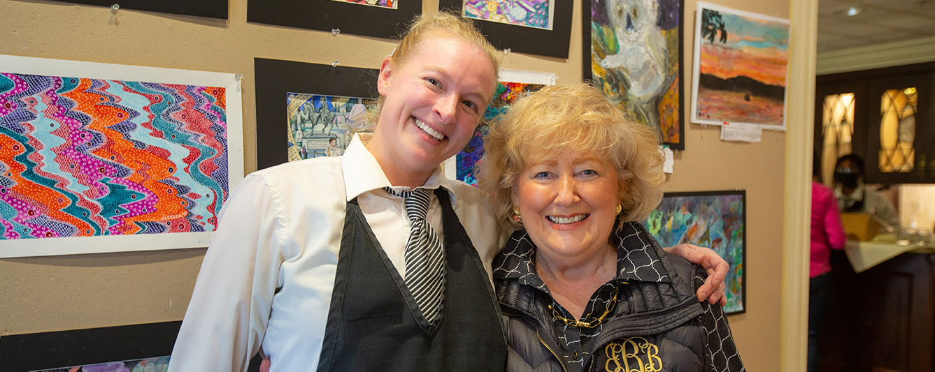 Staff and resident pose for a photo in front of artwork.